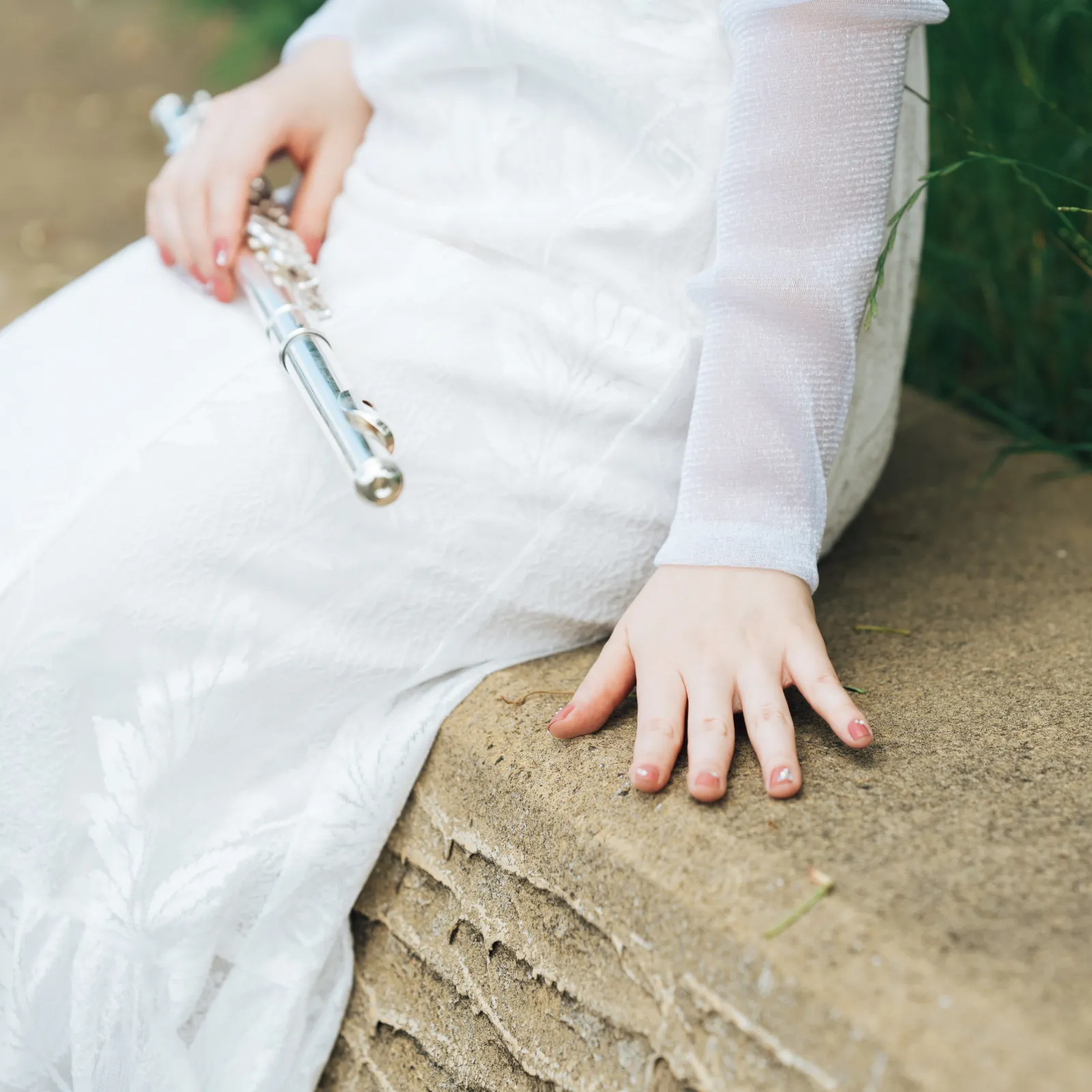 白いドレスを着た永田梨紗がフルートを持って座っている手元のアップの写真