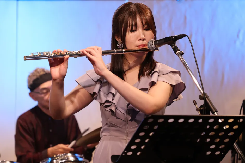 青い照明のステージでフルートを演奏する永田梨紗の写真