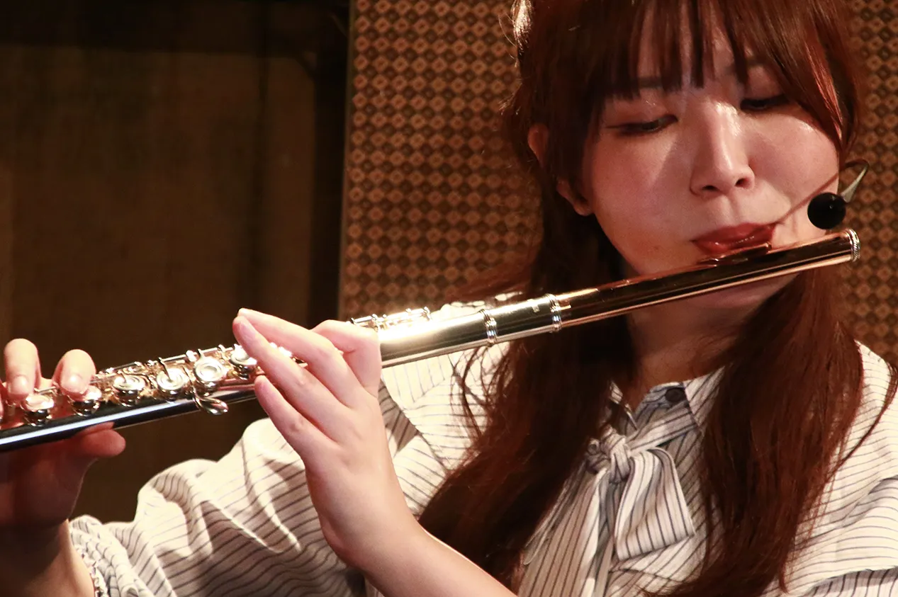 ピンマイクをつけた永田梨紗がフルートを吹く写真